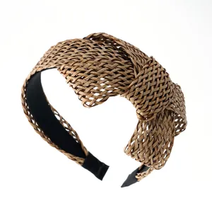 Détail d'un bandeau bohème en raphia montrant la texture de paille marron et le nœud