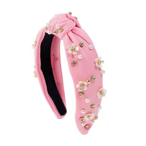 Detail of pink knotted headband featuring white flowers, pearls and colorful rhinestones