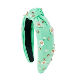 Detail of mint green knotted headband with white camellia flowers, pearls and rhinestones