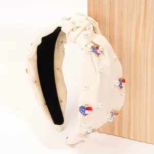 Close-up of cream fabric headband featuring white pearls and heart USA flag charms