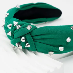 Détail d'un bandeau noué vert avec clous coniques argentés et texture de tricot