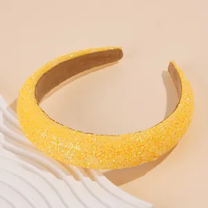 Macro detail of thick yellow sequin headband with soft brown velvet lining for grip