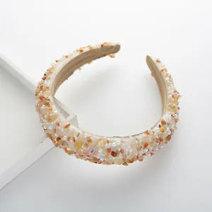 Detailed shot of padded headband with beige stones, white pearls, and soft velvet lining