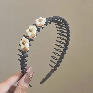 Dettaglio del cerchietto nero ondulato con denti antiscivolo e tre fiori bianchi