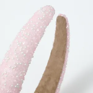 Detailopname van de roze kristallen haarband met witte parels en zachte voering