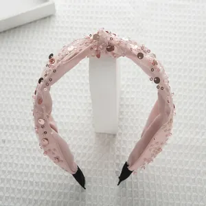 Dettaglio ravvicinato del cerchietto rosa con paillettes e perline e nodo in mesh