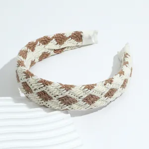 Retro checkered knit headband in brown and beige displayed on a decorative white stand