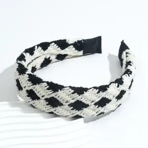 Detailed view of black and white checkered knit headband texture on a white stand
