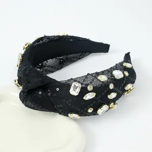 Détail d'un serre-tête noué noir avec paillettes et grands strass en monture griffe