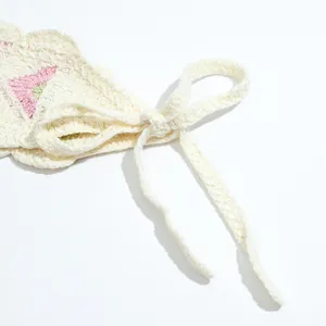 Close-up of handmade crochet headband with pink floral embroidery and lace-up ties