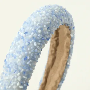 Detail van lichtblauwe en witte harsstenen op een gewatteerde hoofdband met stoffen voering