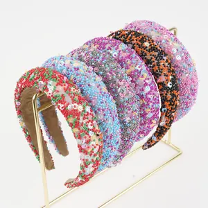 Close-up of handmade sequin beaded headbands with colorful patterns on a metal stand