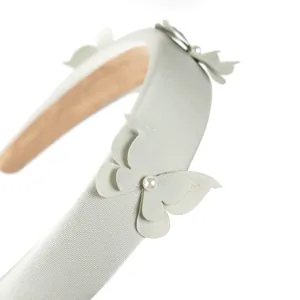 Primer plano de la diadema de esponja verde claro con textura de tela, mariposa y perla