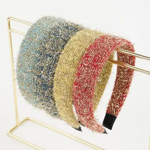 Detail view of plush shiny wide headbands in blue, gold and red on a metal display
