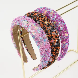 Detailed view of three beaded headbands with colorful sequins on a gold display stand