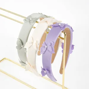 Detalle de diademas acolchadas con lazos de satén y perlas en verde y crema