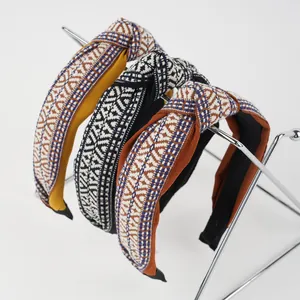 Detailed view of woven knot headbands in yellow, black, and brown with geometric patterns