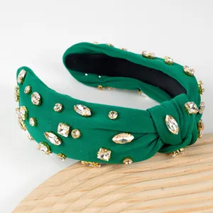Detail of emerald green knotted headband with shimmering crystals on a wooden base
