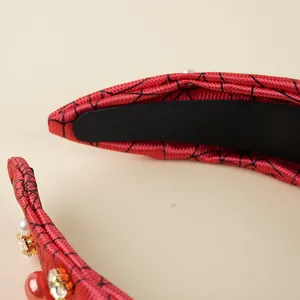 Detail of red Halloween headband with black spider web pattern and pearl accents