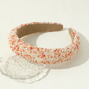Detail van barokke haarband met witte en oranje stenen en een bruine fluwelen voering