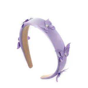 Diadema acolchada de satén lila con mariposas 3D y perlas sobre fondo blanco
