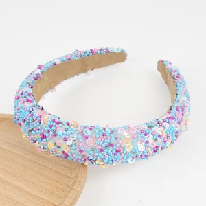 Detail of colorful beaded headband with sequin smiley faces and padded sponge texture