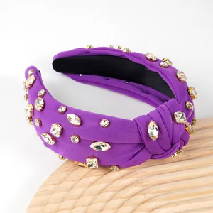 Close-up of purple knotted headband with sparkling rhinestones on wood stand
