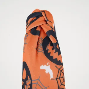 Detailed close-up of Halloween knot headband featuring orange pumpkin and spider web prints