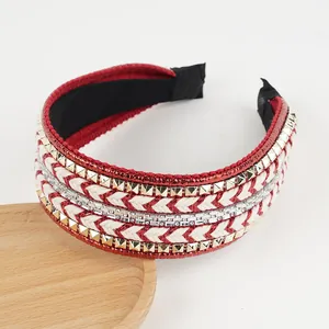 Détail du serre-tête bohème avec rivets dorés, strass argentés et tressage en coton rouge et blanc
