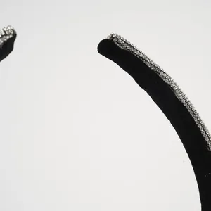 Macro detail of black velvet headband featuring three rows of shiny white rhinestones