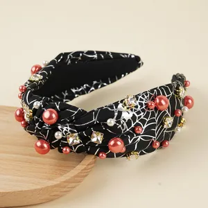 Detail of knotted Halloween headband with silver spider web print and red pearls