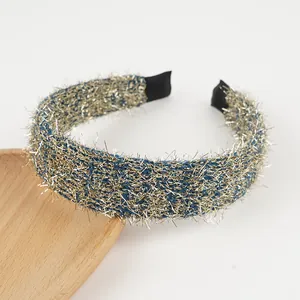 Detail showing the textured metallic gold and blue yarn headband on a wooden tray