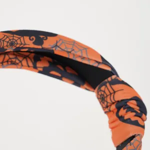 Detail of orange Halloween fabric headband with spider web, bat and pumpkin patterns
