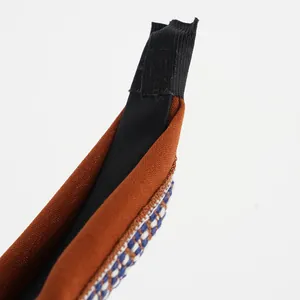 Close-up of brown textured fabric headband with blue and white woven ribbon details