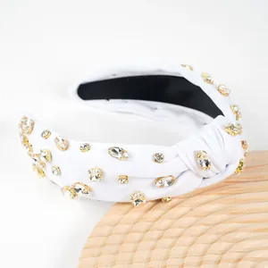 Detail of white knotted headband with sparkling rhinestones and golden base accents