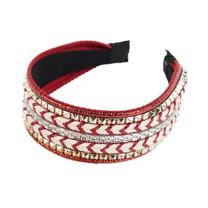 Serre-tête ethnique tissé rouge avec rivets dorés et strass sur un fond blanc épuré