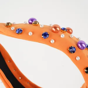 Detailed shot of orange knotted headband with colorful crystals and pearls decoration