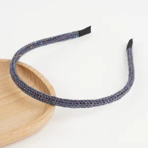 Détail d'un bandeau en maille grise avec fil pailleté sur un plateau en bois