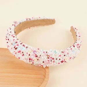 Détail d'un serre-tête rembourré avec pierres colorées et paillettes de sourire sur bois