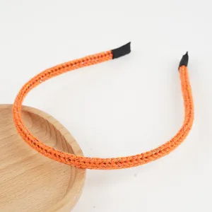 Détail du bandeau tricoté orange vif avec fils scintillants et texture de tissage précise