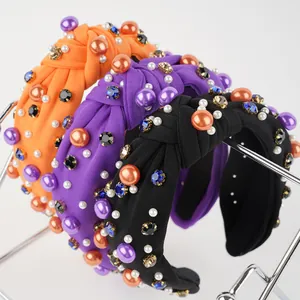 Detail view of knotted headbands with colorful rhinestones and faux pearls on a stand