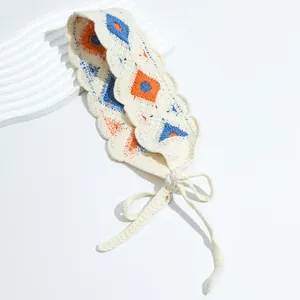 Detail of crochet headband showing orange floral patterns and wavy edges on beige fabric