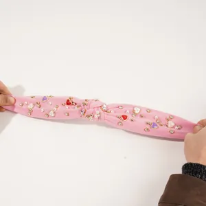 Detailansicht eines rosa Knotenstirnbands mit hoher Elastizität, Perlen und Herzanhängern