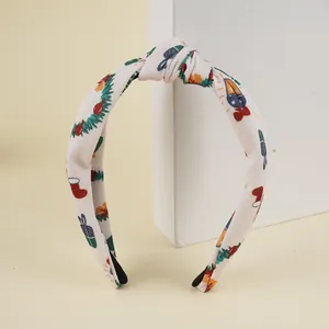 Détail du serre-tête de Noël avec motifs sapins et cadeaux festifs sur tissu beige