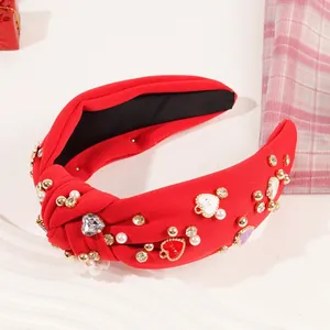 Detail eines roten Stoff-Haarreifens mit Perlen, Strass und Herzanhängern für Damen