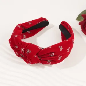 Close-up of red velvet knot headband with silver glitter bow patterns for festive events