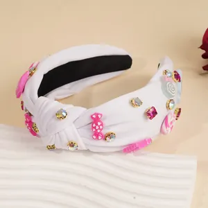 Detail eines weißen Knotenstirnbands mit süßen Bonbon-Anhängern und Strasssteinen