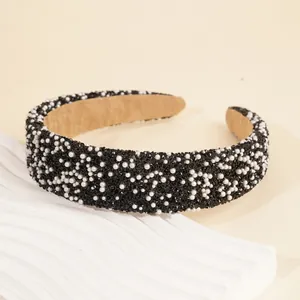 Detail of wide headband with shiny black rhinestones and white pearls on soft fabric