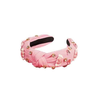 Diadema rosa con pedrería corazón alado y colgante Love sobre fondo blanco
