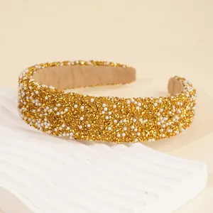 Detail shot of wide headband with glittering gold crystals and white faux pearls